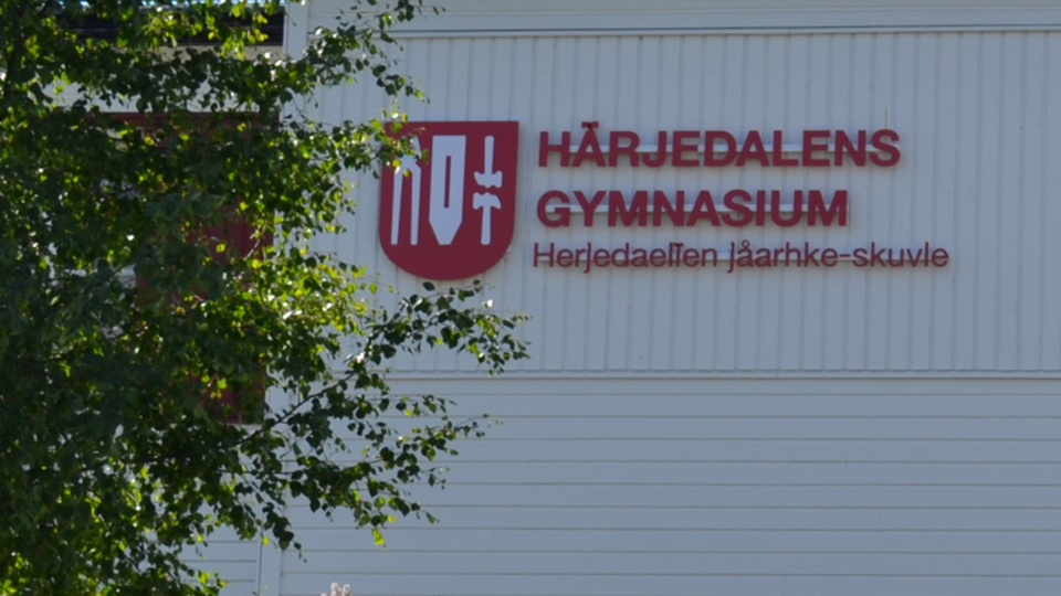 Härjedalens gymnasiums logotyp på vit trävägg.