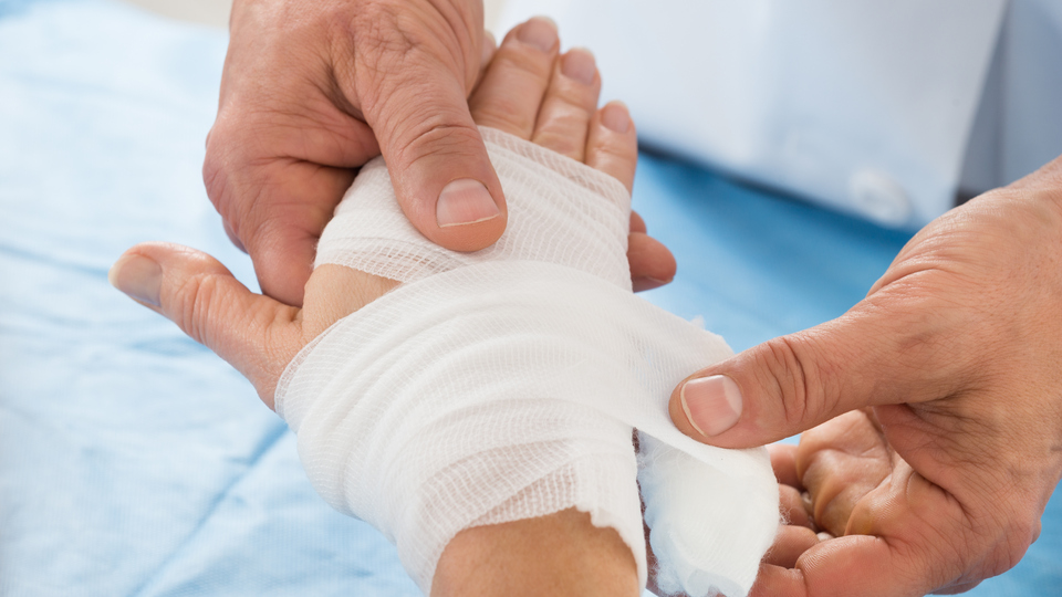 Close-up Of Person Hand Wrapping Bandage To Patient