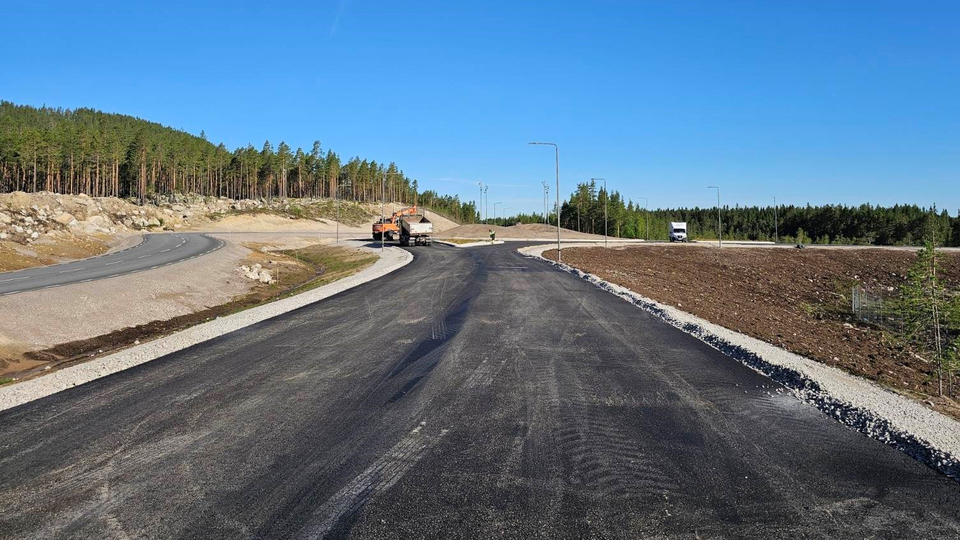 En lastbil som kör längs en väg intill en skog.